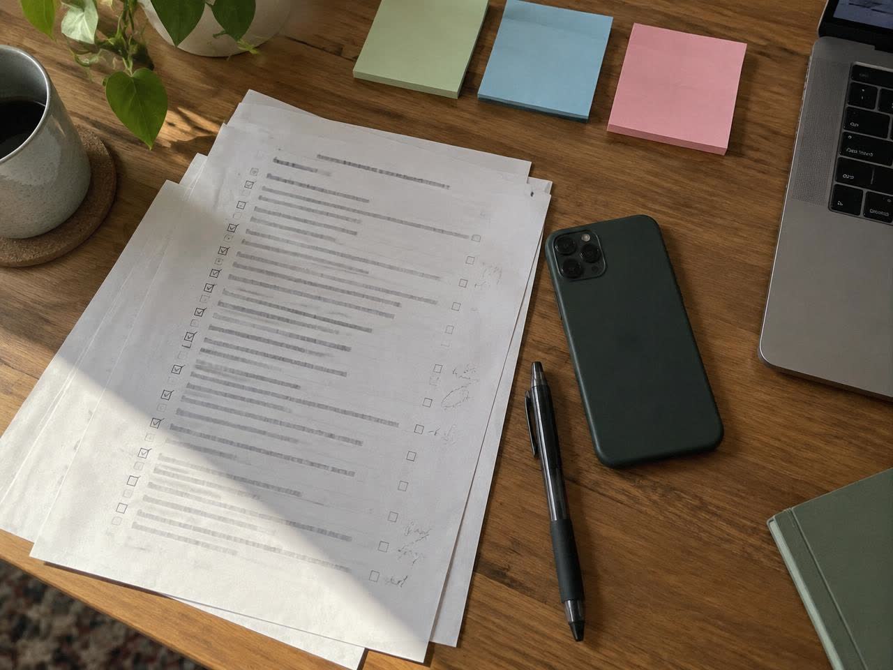 A printed checklist with pen ticks beside a phone on a desk
